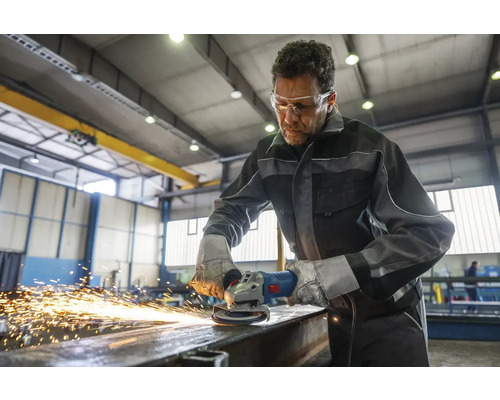 Ein Mann mit Schutzbrille schleift Metall mit einem Winkelschleifer, wobei Funken entstehen.