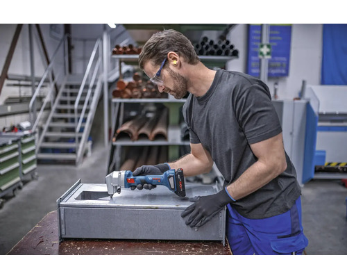 Handwerker schneidet Metall mit einer Akku-Blechschere