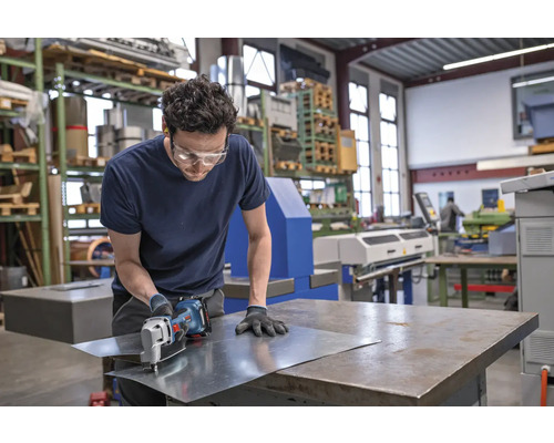 Handwerker schneidet Blech mit einer Blechschere in einer Werkstatt.