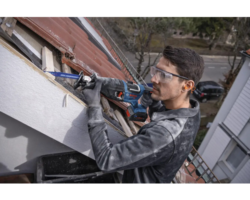 Mann arbeitet mit einer Säbelsäge an einem Dach