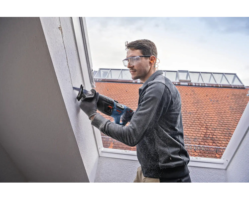 Mann verwendet eine Säbelsäge an einer Wand