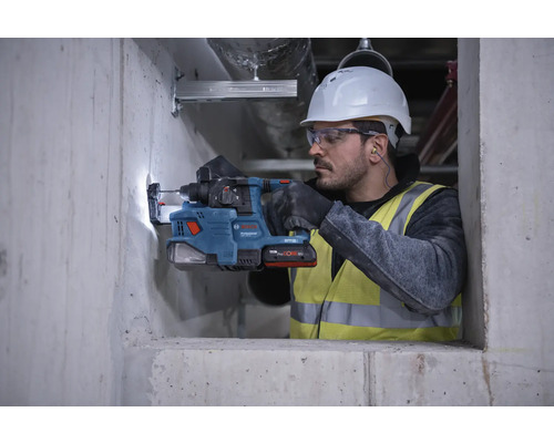 Ein Arbeiter bohrt mit einem Bohrhammer ein Loch in eine Betonwand.