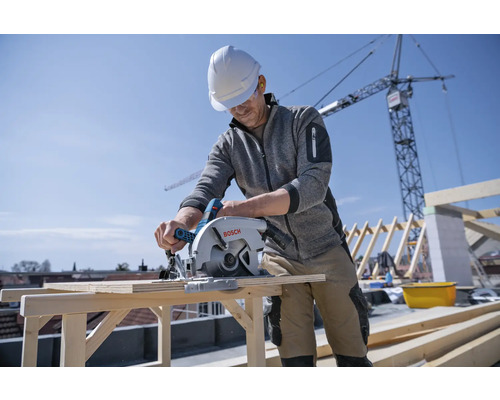 Handwerker sägt Holz mit einer Bosch Kreissäge auf einer Baustelle.