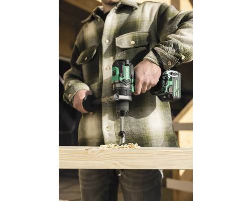 Handwerker bohrt mit einem Akku-Bohrschrauber ein Loch in ein Holzbrett.