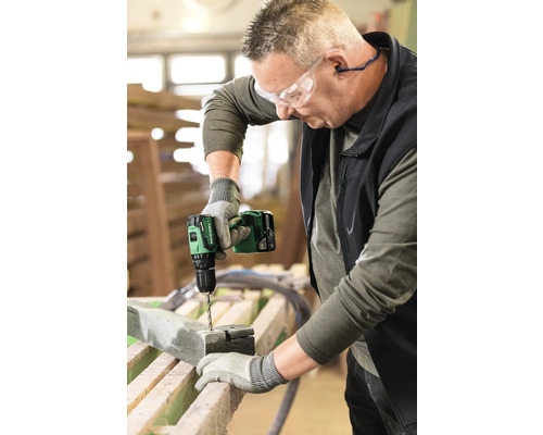 Ein Mann bohrt mit einem Akku-Bohrschrauber ein Loch in ein Werkstück.