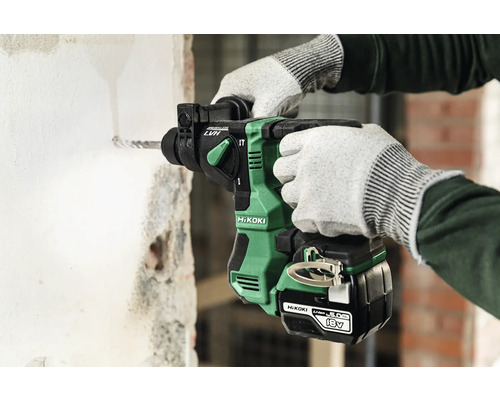 Eine Person bohrt mit einem Akku Bohrhammer ein Loch in eine Wand.