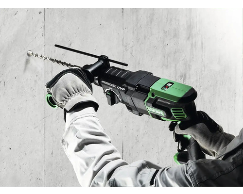 Ein Mann bohrt mit einem Bohrhammer ein Loch in eine Betonwand.