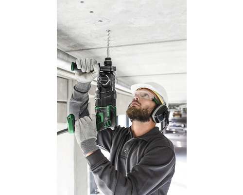 Ein Mann bohrt mit einem Bohrhammer ein Loch in eine Betondecke.