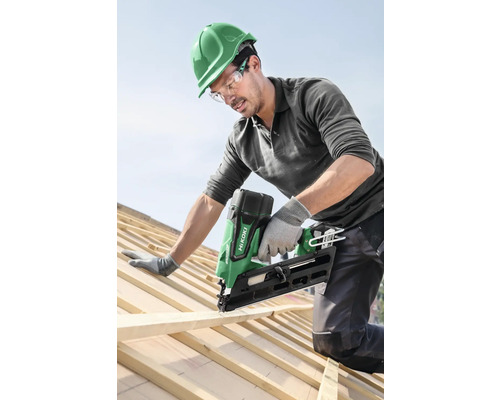Handwerker befestigt Holzlatte mit einem Akku Nagelgerät auf einem Dach