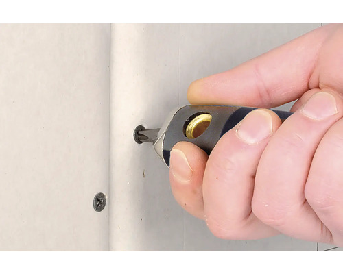 Eine Person schraubt eine Schraube mit einem Schraubendreher in eine Wand.