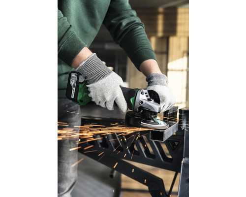 Eine Person benutzt einen Akku-Winkelschleifer zum Schneiden eines Metallstücks mit Funkenflug.