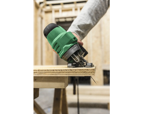 Eine Stichsäge schneidet ein Holzbrett auf einer Werkbank.