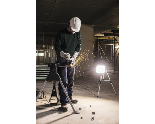 Mann mit Schleifmaschine, Schutzhelm und Arbeitsbock auf einer Baustelle