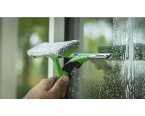 Fensterreinigungswerkzeug mit Mopp und Abzieher im Einsatz auf einer Glasoberfläche