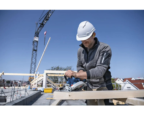 Handwerker sägt Holz mit einer Handkreissäge auf einer Baustelle.