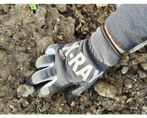 Eine Hand mit Arbeitshandschuh berührt Erde.