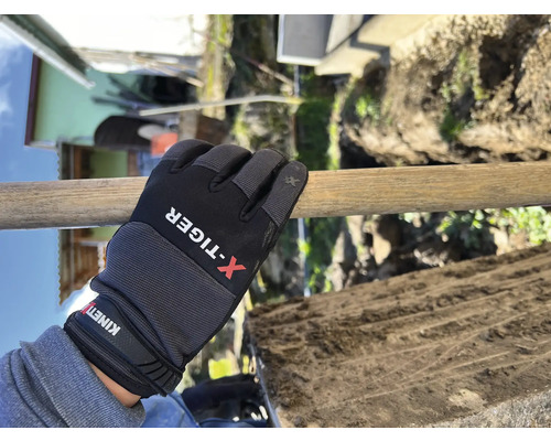 Eine Hand mit Arbeitshandschuh hält einen Spatenstiel beim Graben.
