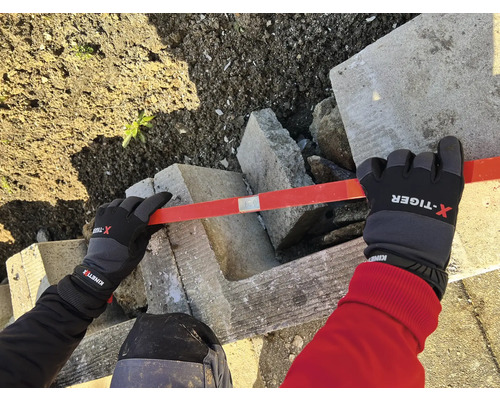 Person mit Handschuhen nivelliert Betonsteine mit einer Wasserwaage