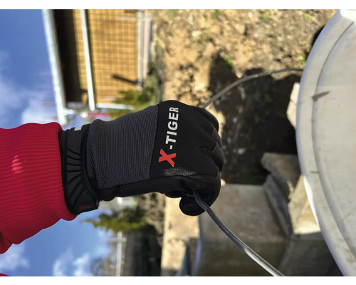 Eine Hand mit X-Tiger-Handschuh hält ein Kabel.