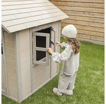 Mädchen öffnet Fenster an einem Spielhaus aus Kunststoff im Garten.