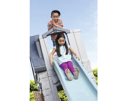 Zwei Kinder spielen auf einer Kinderrutsche im Freien.