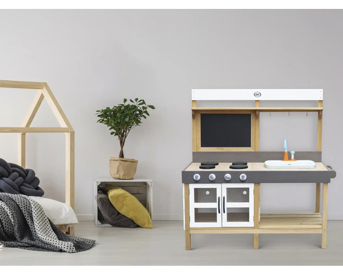 Kinderspielküche aus Holz mit Zubehör und Spielbett im Hintergrund