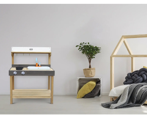 Kinderspielküche aus Holz mit Spüle, Kochfeld und Zubehör neben einem Kinderbett mit Hausrahmen