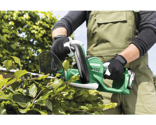 Eine Person schneidet eine Hecke mit einer Akku-Heckenschere der Marke Hikoki.