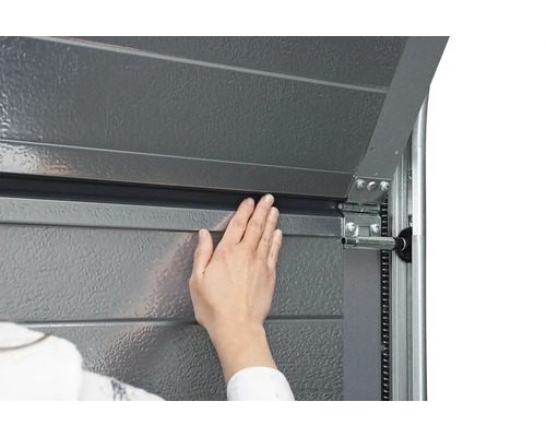 Detailaufnahme eines Garagentors mit Hand zur Dichtungskontrolle