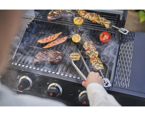 Grill mit Fleisch, Gemüse und Grillspießen auf dem Grillrost