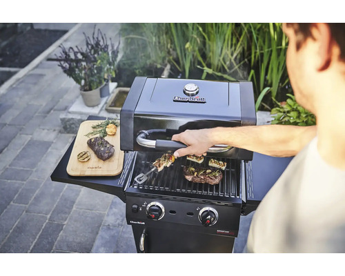Char-Broil Gasgrill mit Grillgut und einem Mann, der den Grill bedient