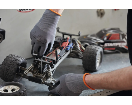Eine Person repariert mit Schutzhandschuhen ein ferngesteuertes Auto.