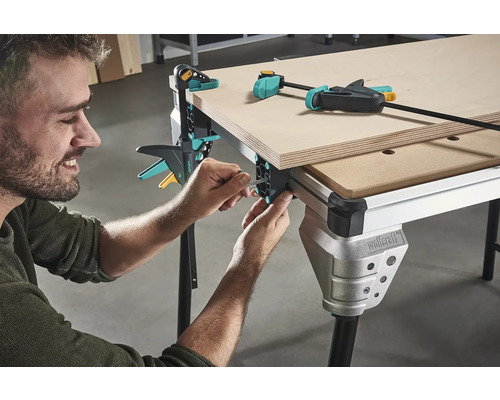 Mann montiert Werkbank mit Schraubzwingen zur Holzbearbeitung