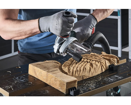 Ein Handwerker bearbeitet ein Holzstück mit einer Oberfräse auf einer Werkbank.