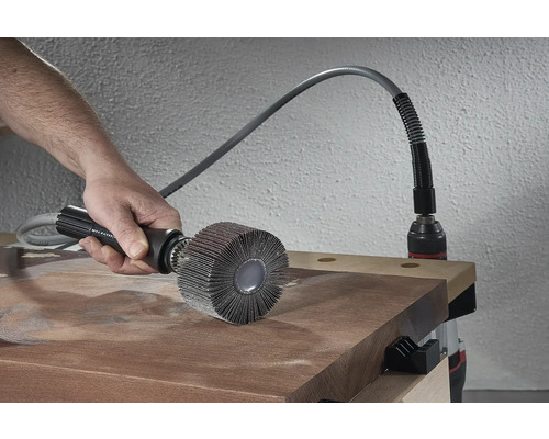 Eine Person verwendet eine Bürstenschleifscheibe mit biegsamer Welle zum Schleifen eines Holzstücks.