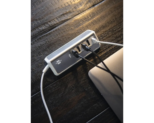 USB-Hub mit mehreren Anschlüssen und angeschlossenen Kabeln auf einem Holztisch