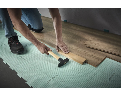 Verlegen von Laminat mit Hammer und Schlagholz auf Dämmunterlage