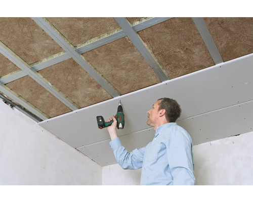 Mann montiert eine Deckenverkleidung mit einem Akkuschrauber