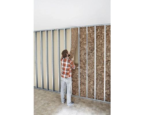 Mann bringt Dämmmaterial in einer Metallständerwand an