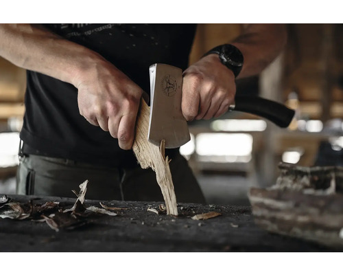 Mann spaltet Holz mit einer Axt.