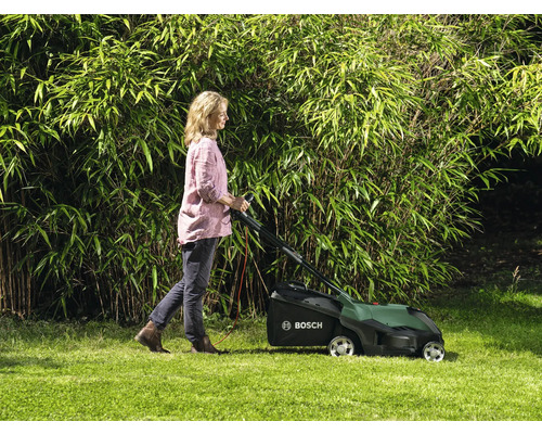 Frau benutzt Rasenmäher im Garten