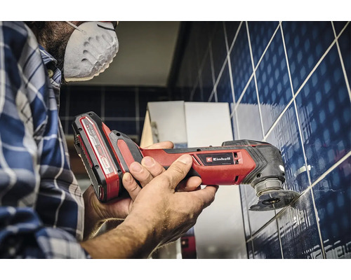 Ein Mann arbeitet mit einem Einhell Multifunktionswerkzeug an Fliesen.