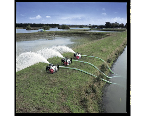 Drei Wasserpumpen in Betrieb auf einer grünen Wiese neben einem Gewässer