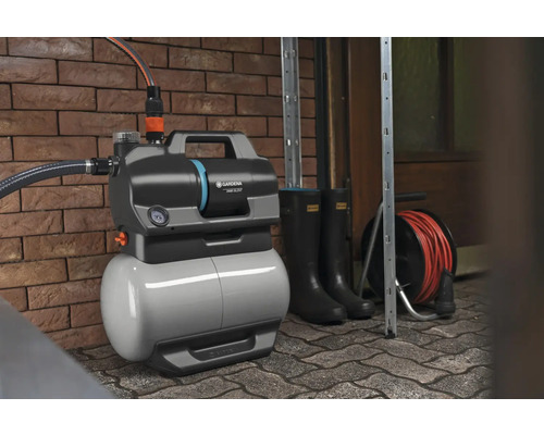 Gartenpumpe mit Zubehör vor einer Ziegelwand