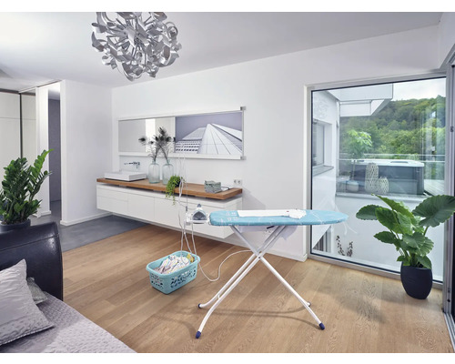 Wohnraum mit Bügelbrett, Bügeleisen, Wäschekorb und Zimmerpflanzen