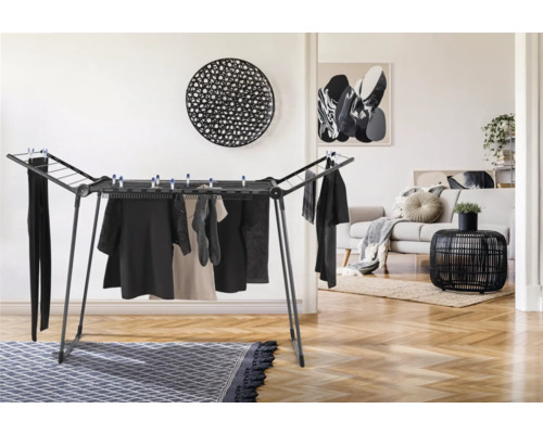 Wäscheständer mit aufgehängter Kleidung in einem hellen Wohnraum.