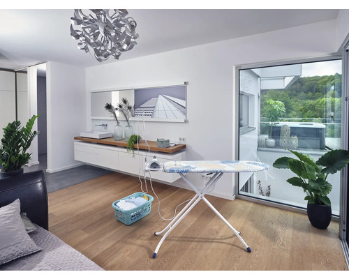 Bügeleisen mit Wäschekorb in einem hellen Wohnraum.