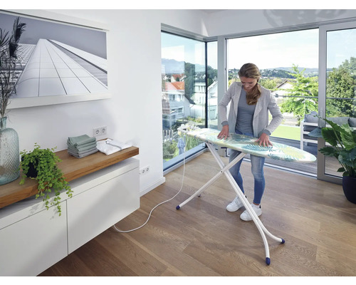 Frau bügelt auf einem Bügeltisch in einem hellen Raum
