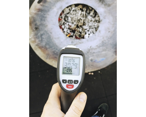 Eine Infrarotthermometer-Messung wird an einer Feuerschale mit Kohle durchgeführt.