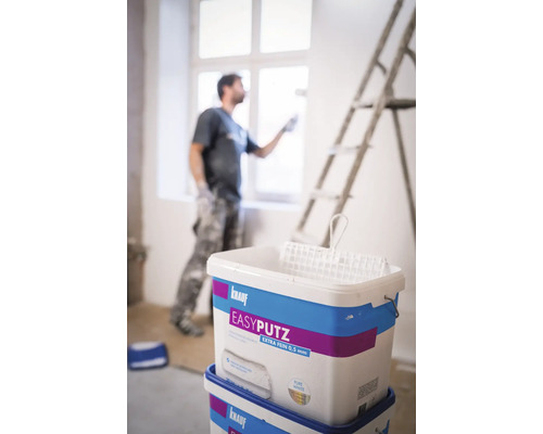 Zwei Eimer Knauf Easyputz Extra Fein 0.5 mm mit Maler und Leiter im Hintergrund